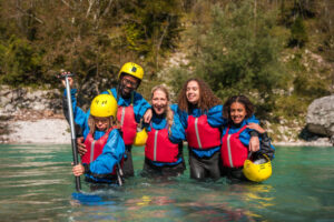 Multiracial family with life jackets and helmets enjoying water sports together, surrounded by natural beauty.